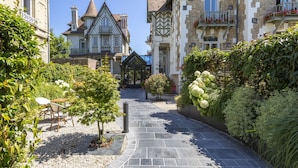 Ein Innenhof mit einem Kopfsteinpflasterweg, umgeben von üppigem Grün und einem Kiosk.
