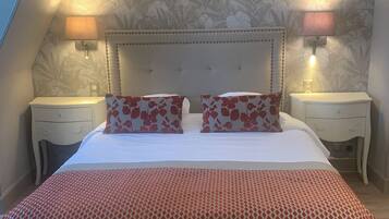 Une chambre à coucher avec un lit, deux tables de chevet, une tête de lit et un mur décoré d’un motif.