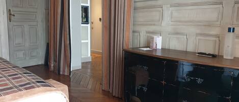 A hotel room with a bed, a desk, a television, and a minibar.