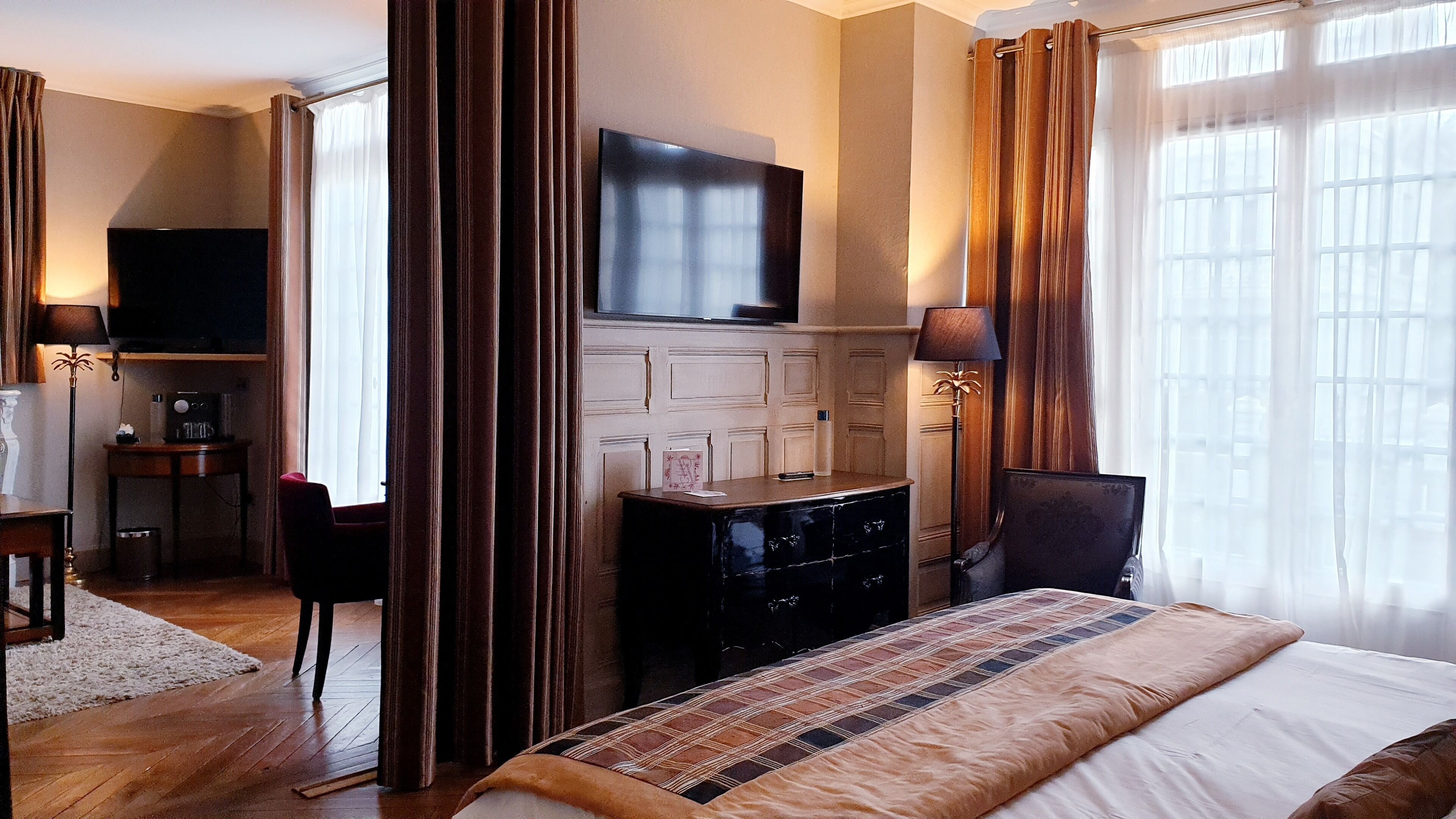 A hotel room with a bed, a desk, a television, and a chair.
