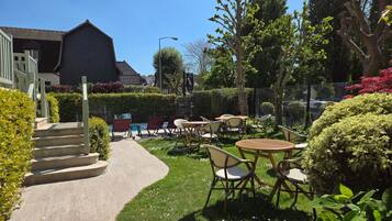 A garden patio with outdoor seating, a pool, and a building in the background.