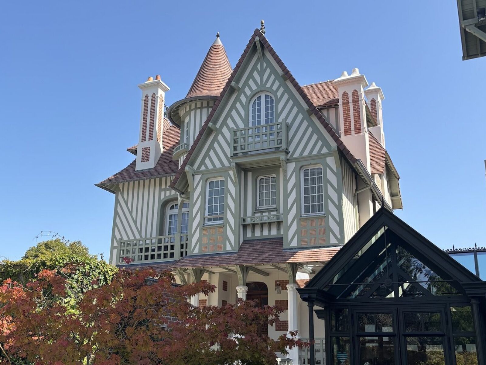 A large, multi-story building with a prominent tower, multiple windows, and a steeply pitched roof.