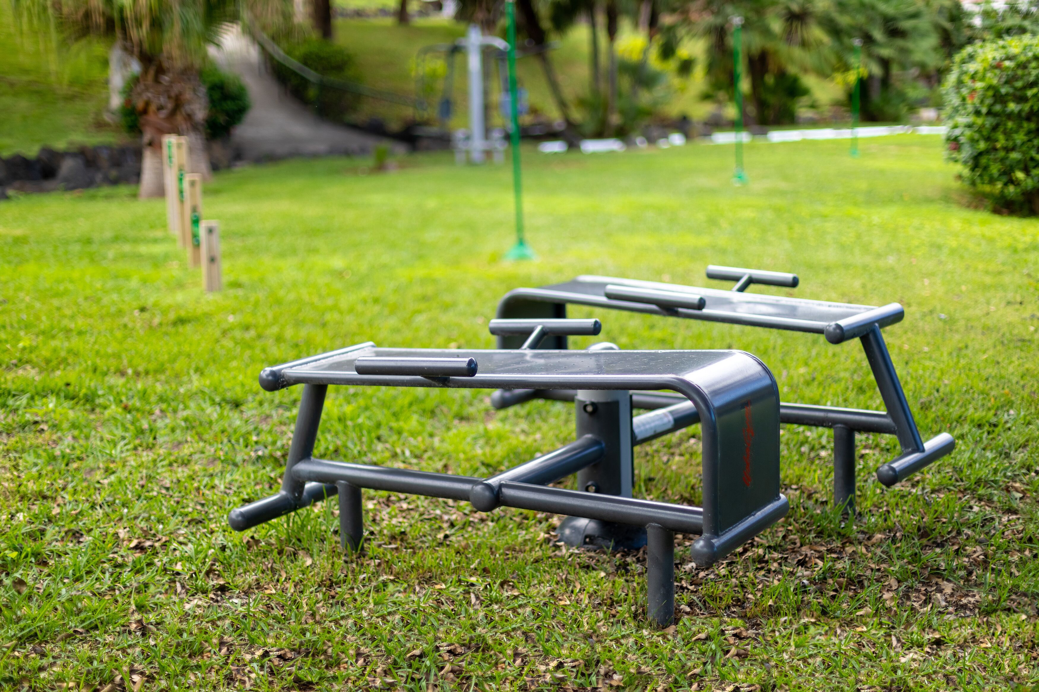 Una mesa de picnic metálica en un parque cubierto de césped.