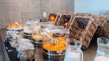 A buffet area with various food items, including jars of cereal, fruit, and a milk dispenser.