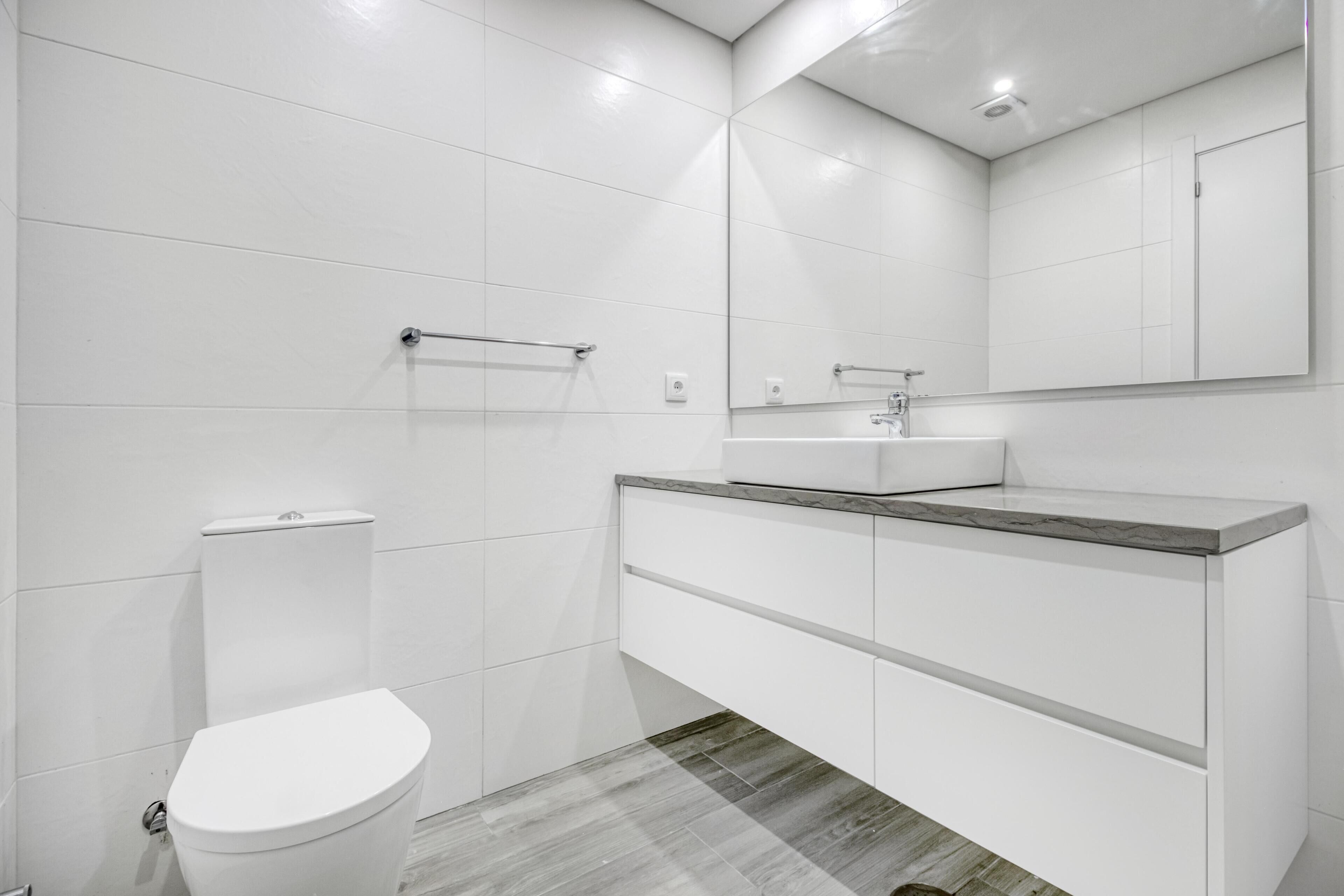 Een moderne badkamer met toilet, wastafel en spiegel.