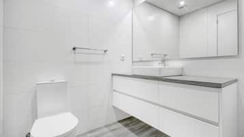 A modern bathroom with a toilet, sink, and mirror.