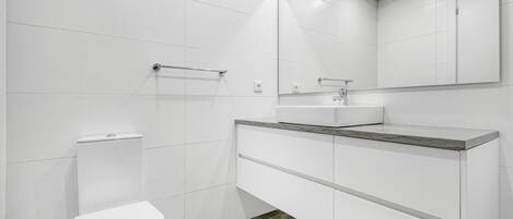 Un baño moderno con inodoro, lavabo y espejo.