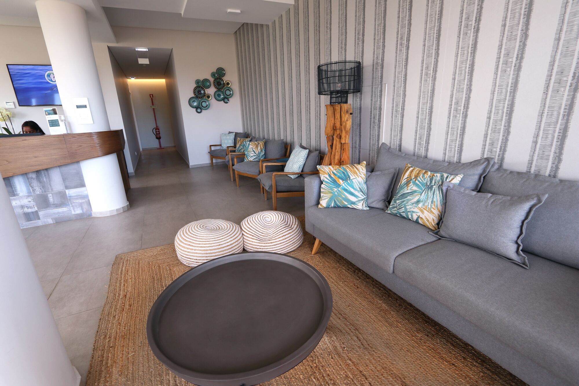 Una sala de estar moderna con un sofá gris, dos sillones, una mesita de centro y una alfombra estampada.