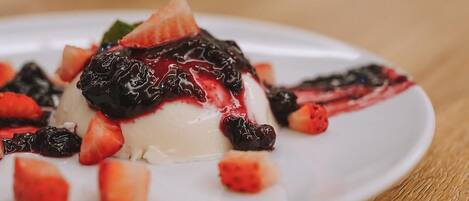 Dessert auf weißem Teller mit Erdbeeren und dunkler Sauce.