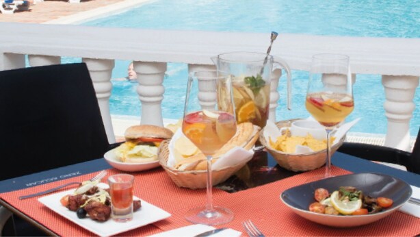 A dining table with various dishes and drinks, overlooking a pool. - Agua Hotels Vila Branca (Lagos)