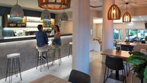 A modern bar area with high stools, pendant lighting, and a bar counter displaying bottles and glasses. - Agua Hotels Vila Branca (Lagos)