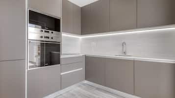 Een moderne keuken met inbouwapparatuur, een roestvrijstalen spoelbak en een verlichte backsplash.