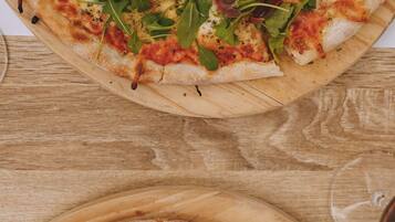 Two pizzas on wooden boards, one topped with greens and the other with mushrooms and ham.