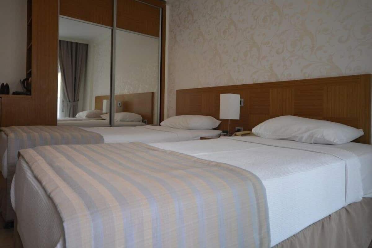 A hotel room with two beds, a large mirror, and a wooden headboard.