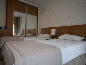 Habitación de hotel con dos camas, un espejo grande y un cabecero de madera.