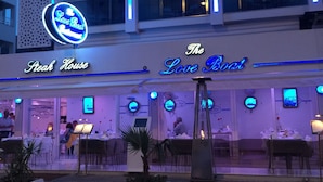 A restaurant named 'The Love Boat' with a neon sign, outdoor seating, and a view of the dining area. - Hotel Devamlı (Marmaris)