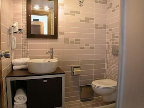 Un baño con lavamanos, inodoro y espejo.