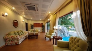 A spacious living area with a sofa set, armchairs, a coffee table, and a view of a pool. - Hotel Devamlı (Marmaris)