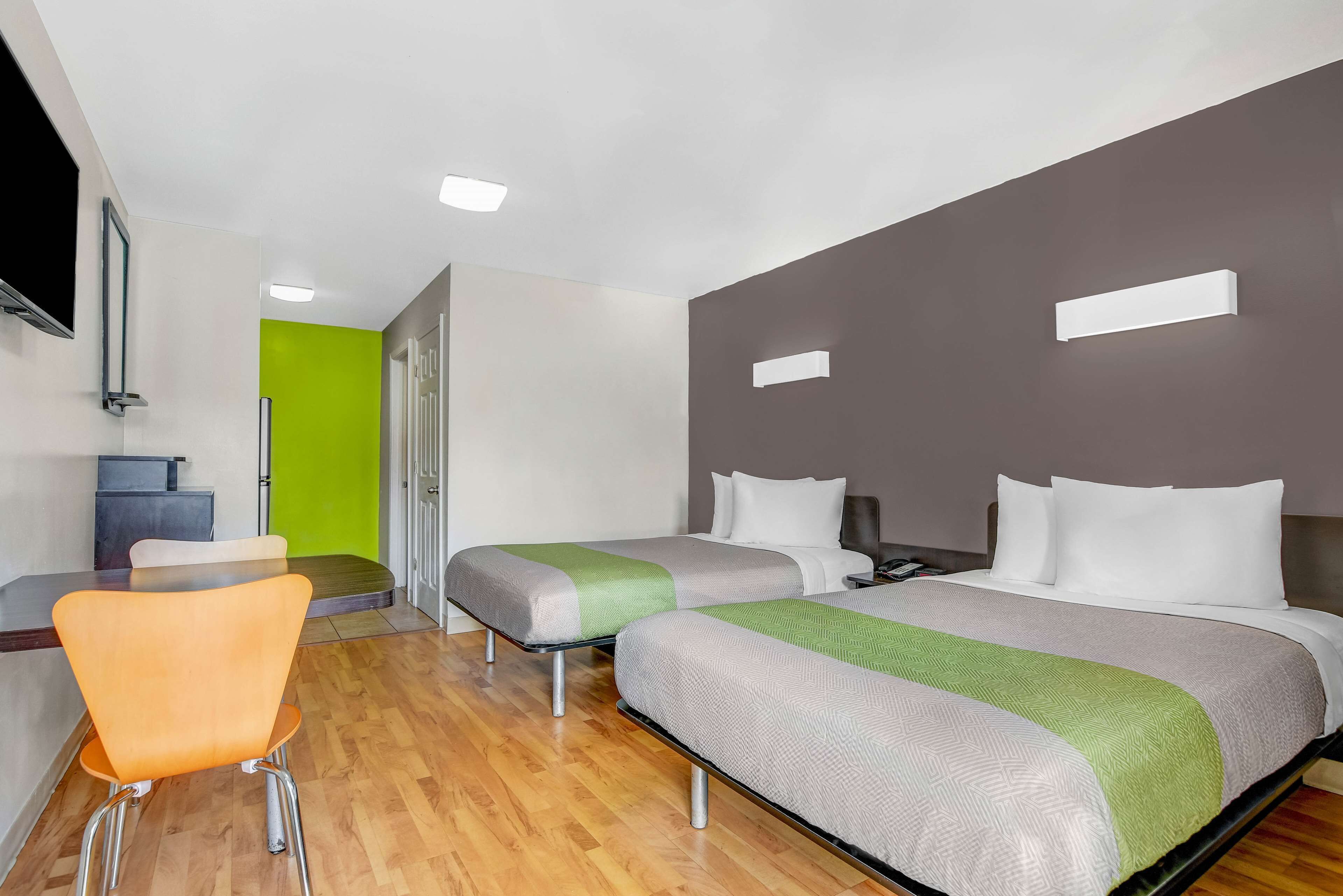 A hotel room with two beds, a desk, and a chair.