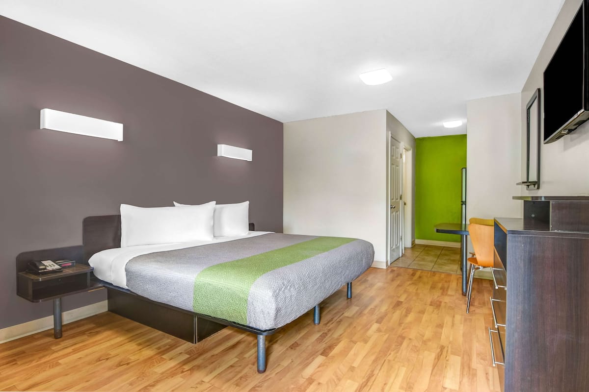 A modern hotel room with a bed, bedside table, and a desk area.