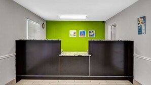 A reception area with a green wall, a black reception desk, and a white ceiling light. - Studio 6 Extended Stay - Atlanta, GA - Chamblee (Chamblee)