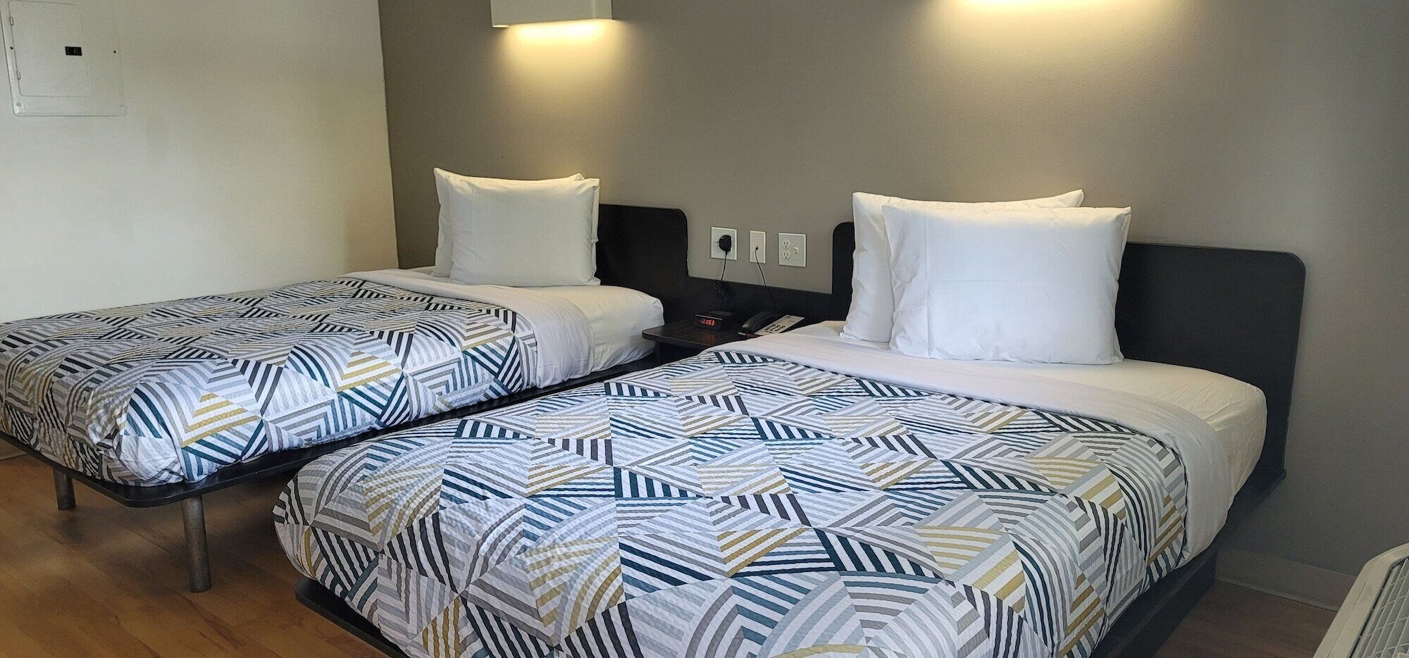 Habitación de hotel con dos camas, cada una con ropa de cama estampada y almohadas blancas.