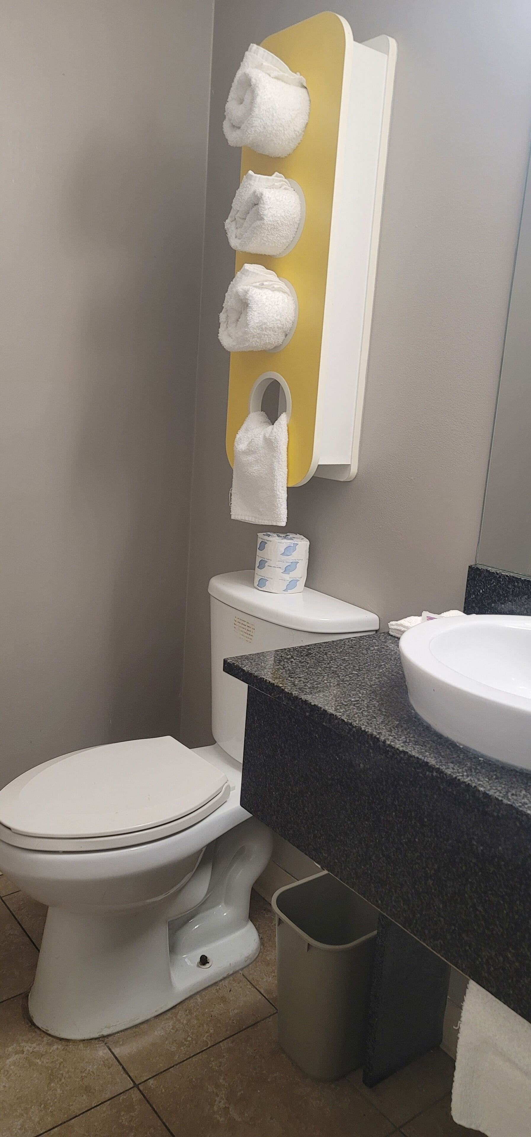 A bathroom with a toilet, sink, and a towel rack with multiple towels.