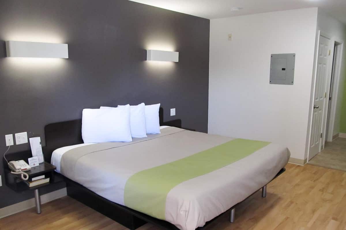 A modern hotel room with a large bed, bedside tables, and wall-mounted lighting.
