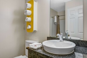 A bathroom with a sink, toilet, and a towel rack with towels. - Studio 6 Extended Stay - Atlanta, GA - Chamblee (Chamblee)
