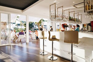 Zona de bar con taburetes altos, barra y vitrina con botellas.