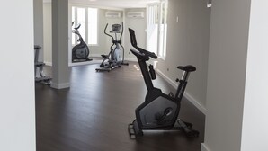 A spacious home gym with a variety of exercise equipment, including stationary bikes and a treadmill, in a well-lit room with large windows. - Hotel Globales Cala Blanca (Ciutadella de Menorca)