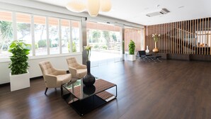 A spacious lobby with a modern design, featuring a seating area with two chairs, a coffee table, and a large window offering a view of the outdoors. - Hotel Globales Cala Blanca (Ciutadella de Menorca)