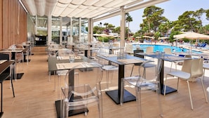A restaurant with outdoor seating overlooking a pool, featuring clear chairs and tables.
