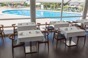 Un restaurante con mesas dispuestas para comer, con vista a una piscina.