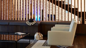 A modern interior with a wooden slatted partition, a staircase, a white armchair, and a glass coffee table. - Hotel Globales Cala Blanca (Ciutadella de Menorca)