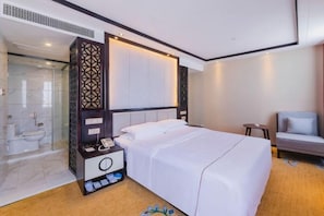 Une chambre d’hôtel comprenant un lit, une table de chevet, une chaise, un espace douche et un grand miroir.