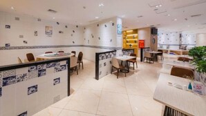 Un vestíbulo de hotel con un área de estar central, una recepción y una planta.