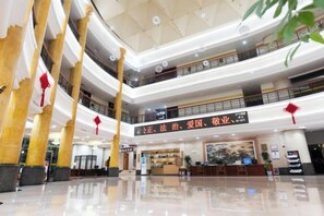 Un atrium à plusieurs niveaux comprenant un comptoir d’accueil, de grandes colonnes et un sol poli.