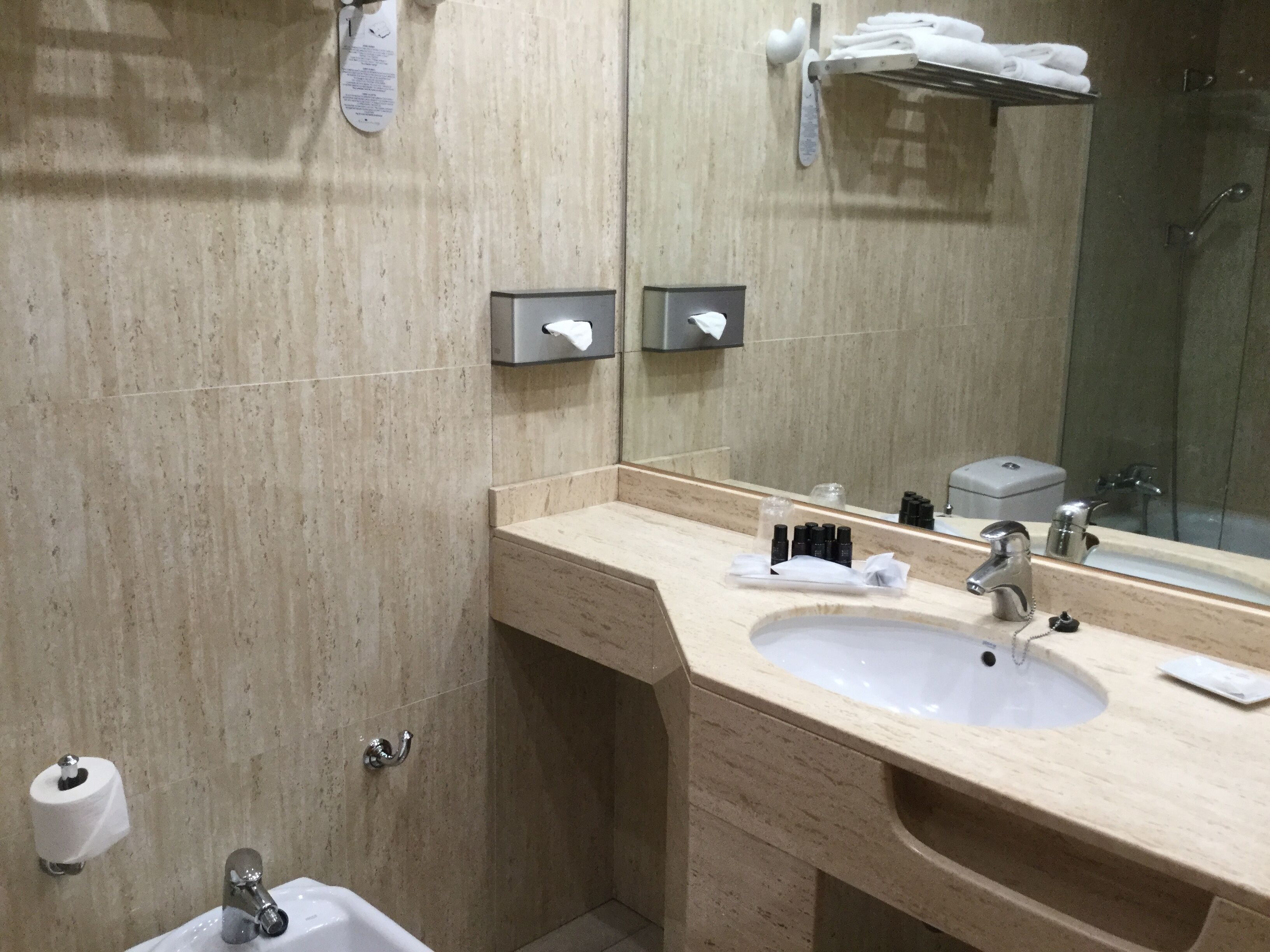 Un baño moderno con encimera color crema, un lavamanos, un espejo y un perchero para toallas.
