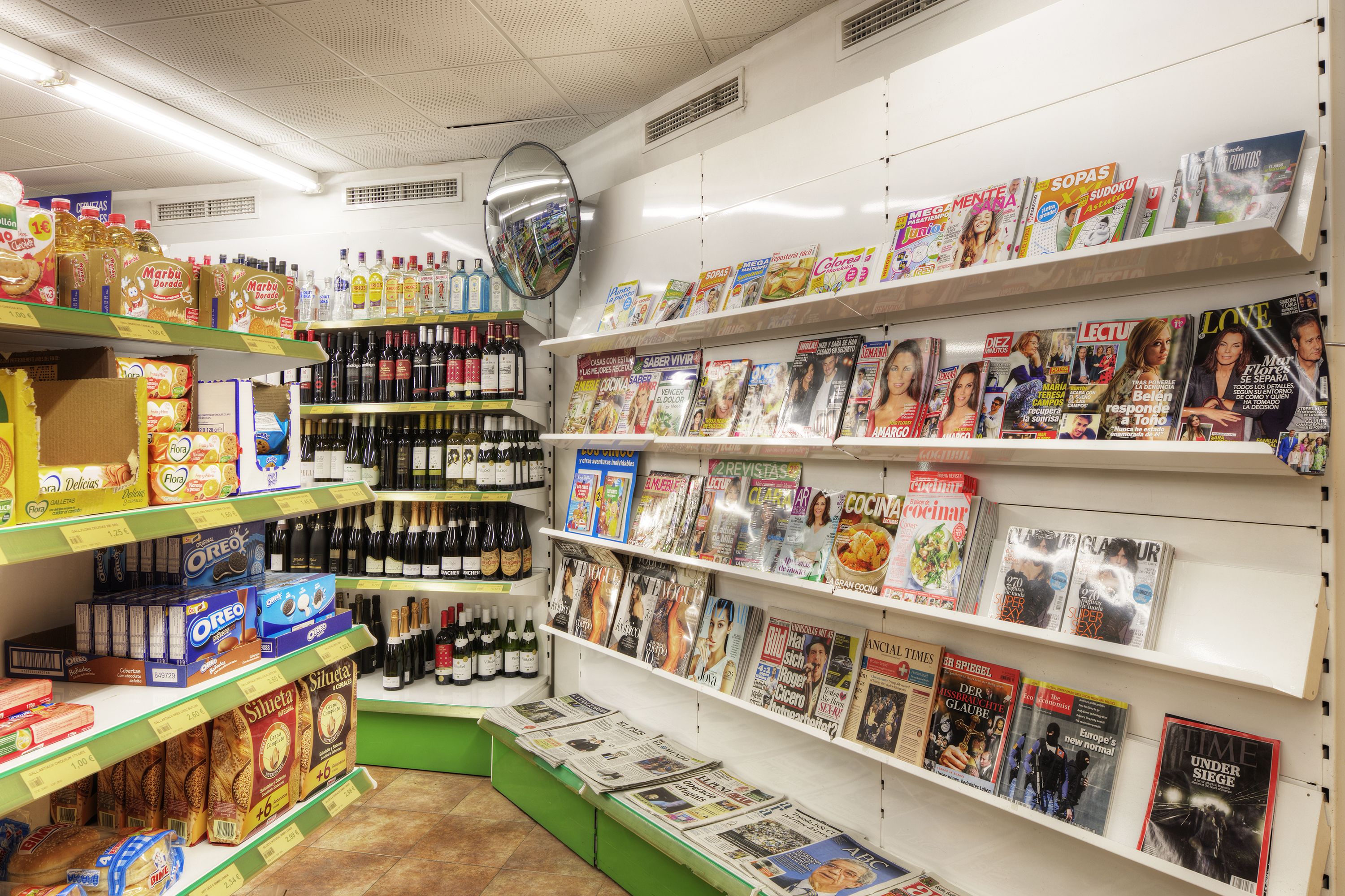 A bookstore with shelves of magazines and books, and a section with snacks and drinks.