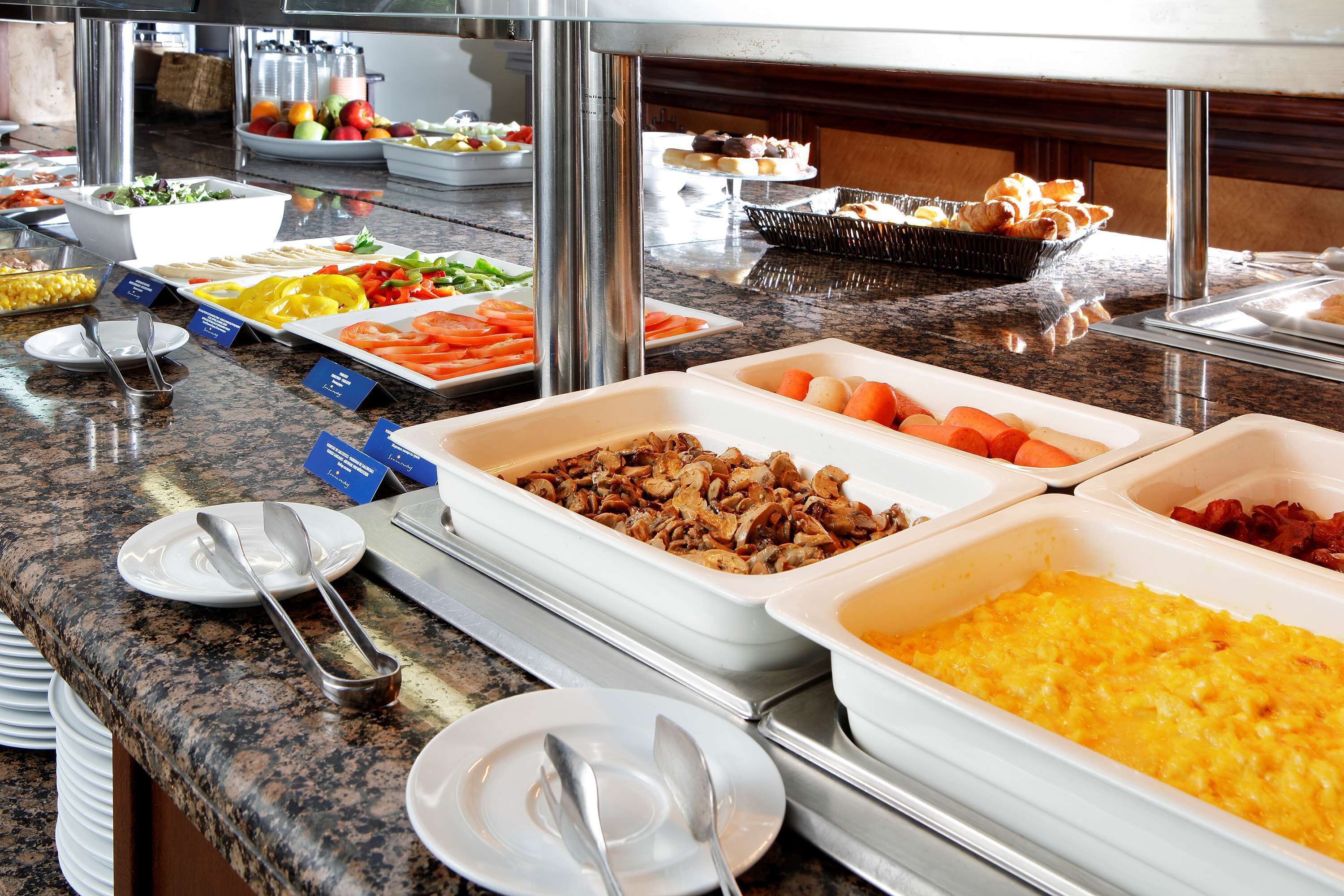 Ein Buffet mit verschiedenen Speisen, darunter Obst, Gemüse und bereits zubereitete Gerichte.