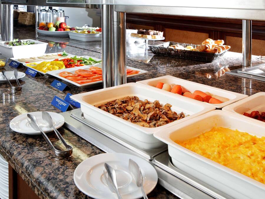 Un bufé con diversas opciones de comida, incluyendo frutas, verduras y platos preparados.