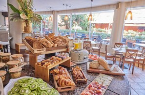 A breakfast buffet with various food items, including pastries, bread, and fruits, in a well-lit indoor setting with large windows. - Hotel Sunway Playa Golf & Spa Sitges (Sitges)