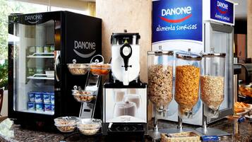 A buffet area with Danone refrigerated display cases, a coffee machine, and various food dispensers.