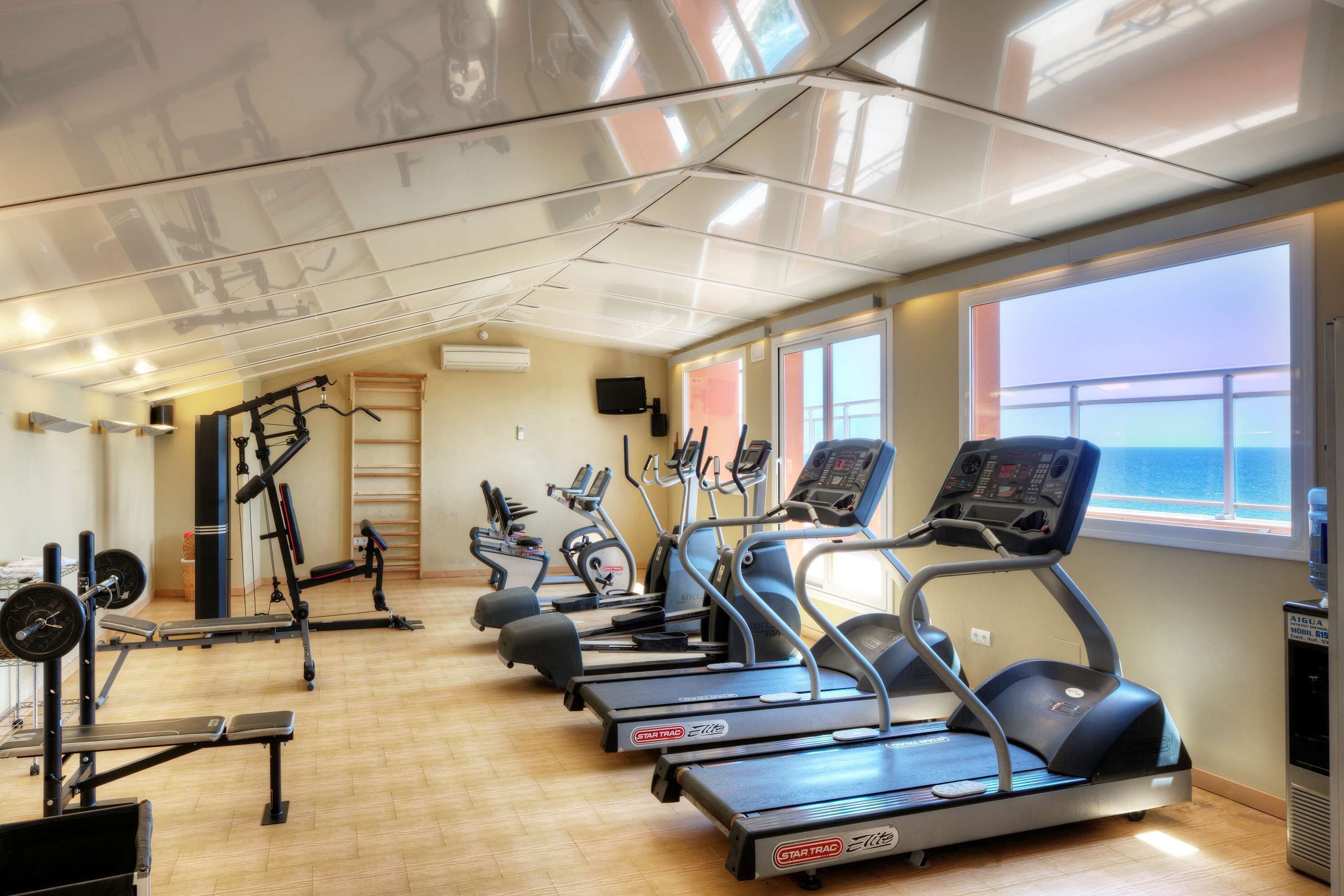Un gimnasio con cintas de correr, elípticas y bancos de pesas.