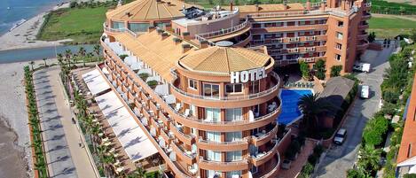 A hotel with a circular central tower, multiple balconies, and a pool.