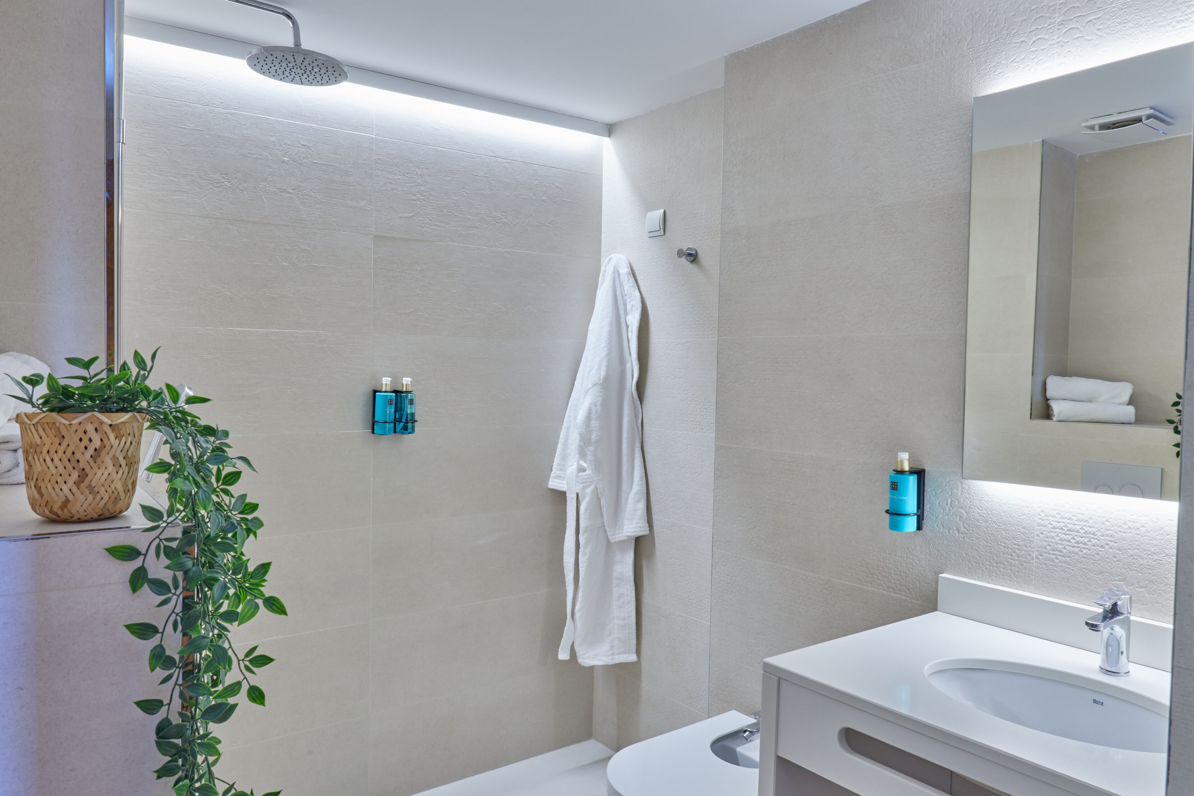 A modern bathroom with a shower, white sink, and a large mirror.
