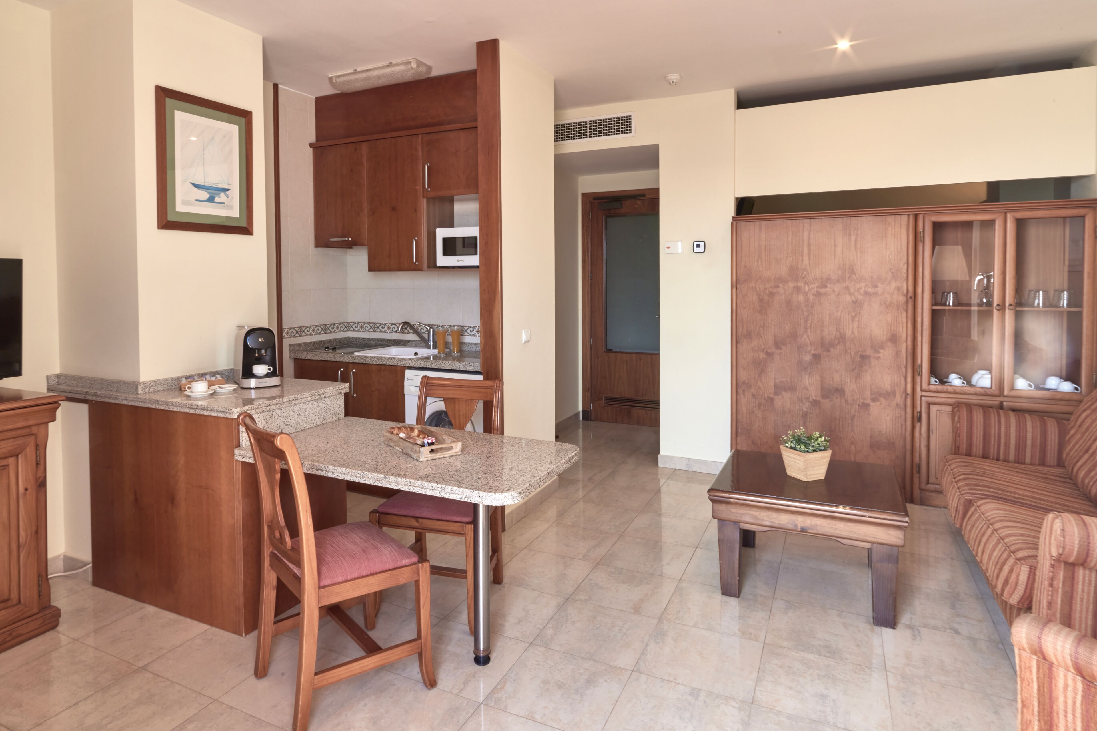 A modern kitchen with wooden cabinets, a built-in microwave, and a dining area with a table and chairs.