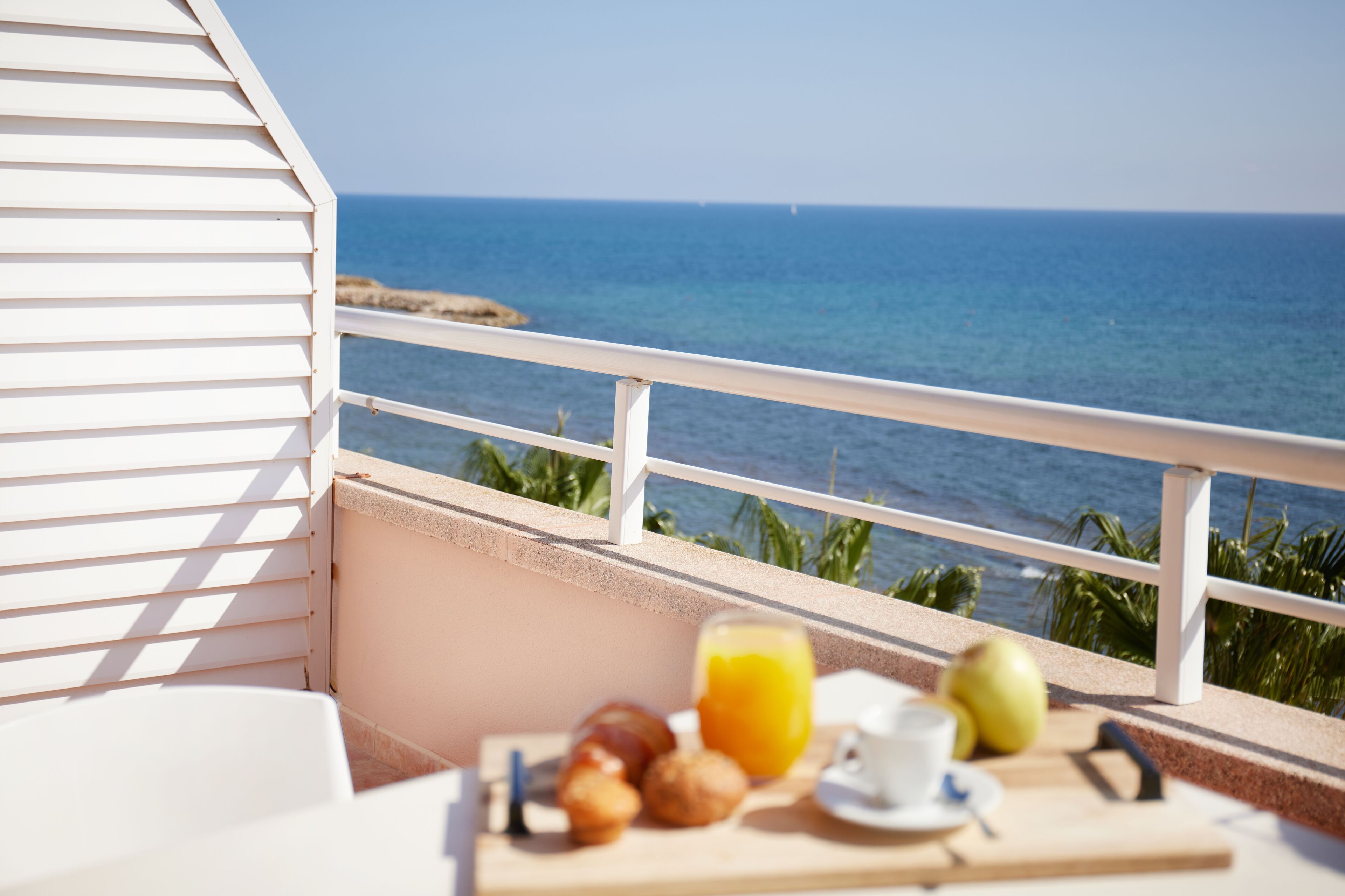 Ein Balkon mit Frühstückstisch, mit Blick auf das Meer.