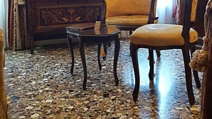 Una habitación con alfombra estampada, un armario de madera, un sofá y una silla.